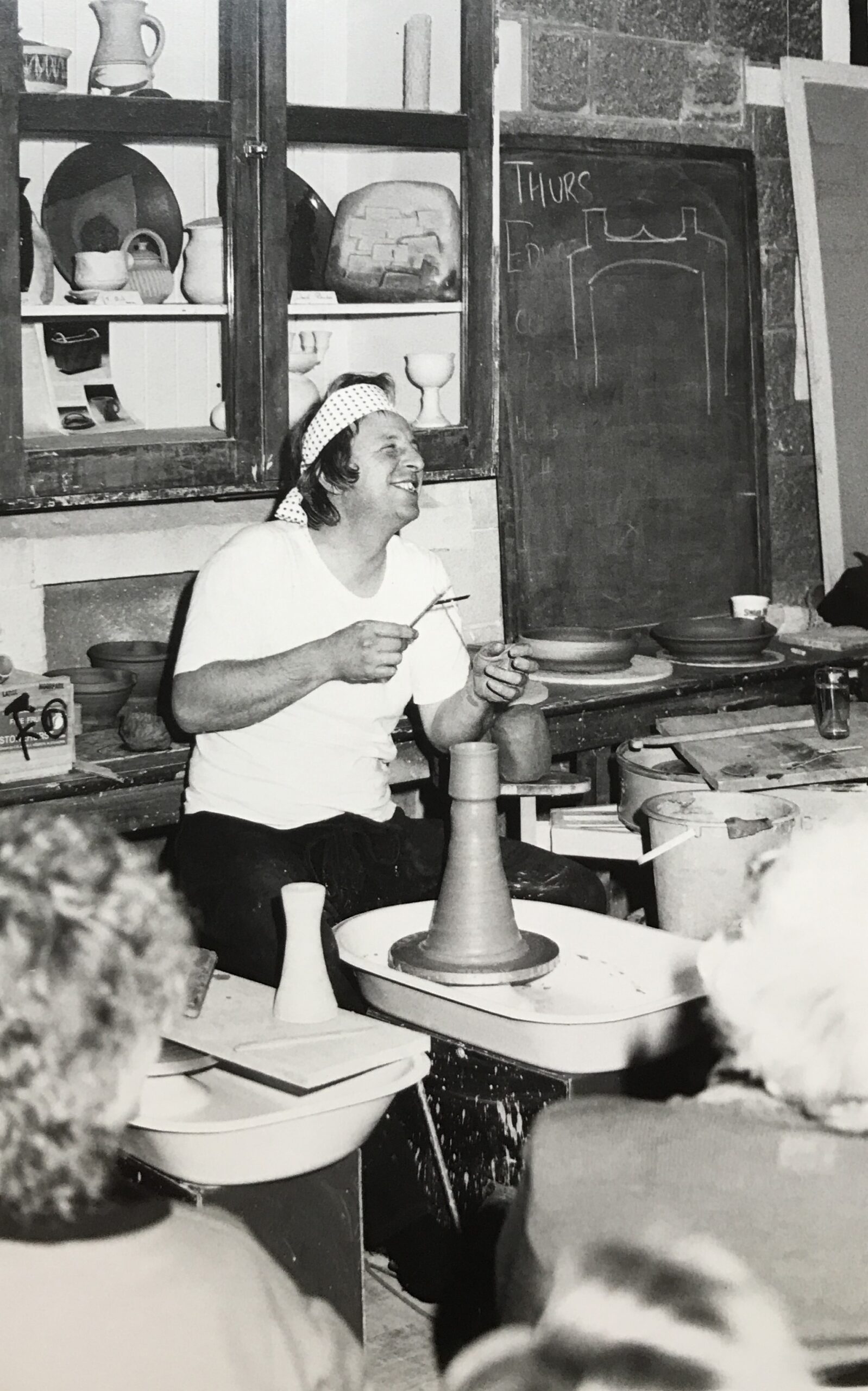 Black and white photograph of unknown potter demonstrating clay on a pottery wheel at Canterbury Pottery Group's clubrooms, circa 1950/60.